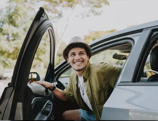 man smiling as he's getting out of his car