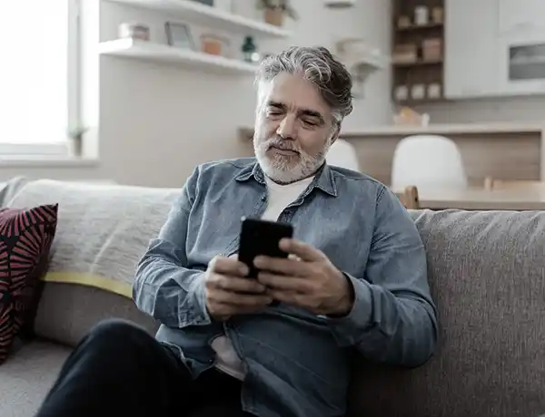 gentleman looking at his phone on his couch