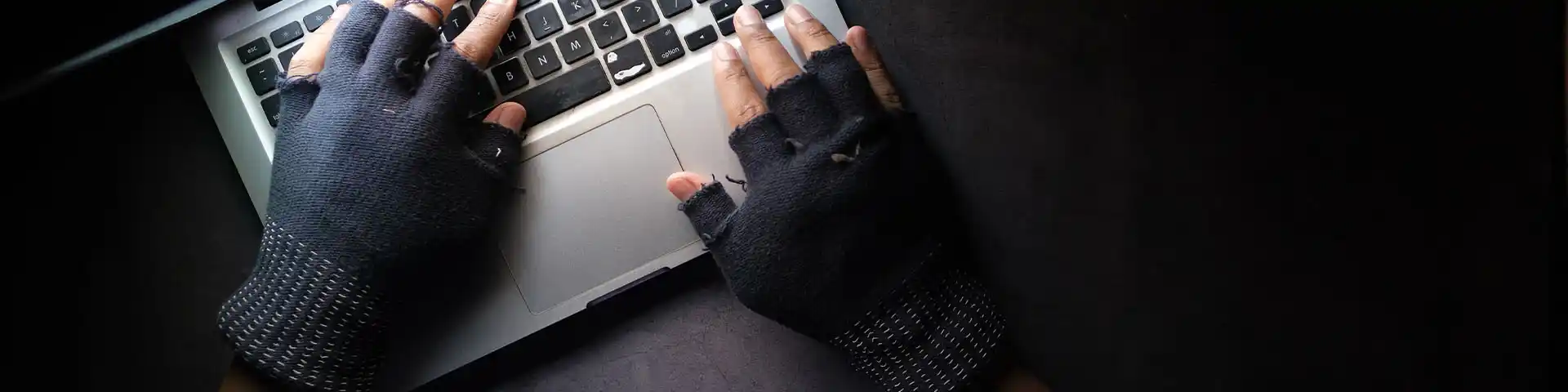 suspicious user wearing gloves trying to access a laptop