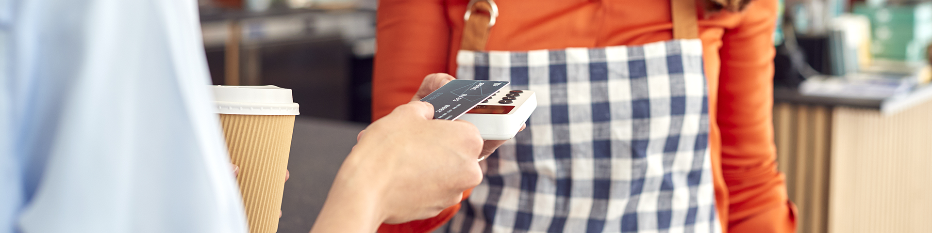 A person paying for coffee with a debit card