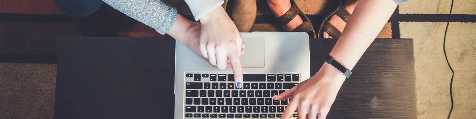 two sets of hands managing a laptop